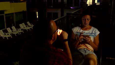man and woman sitting on the balcony to smoke
