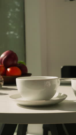 tazas, ingredientes de té y frutas en la mesa. composición con tazas de cerámica pequeños frascos de especias y hierbas secas. postre saludable en la cocina