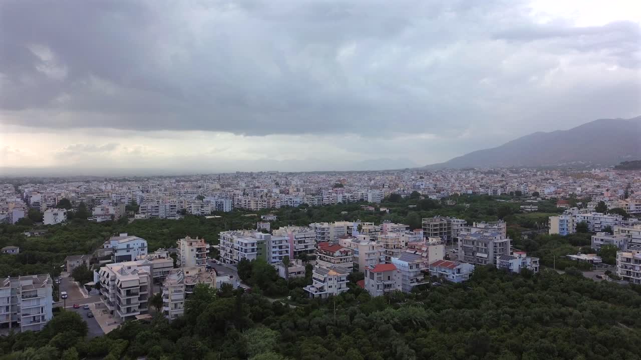 Aerial push in, establishing footage of Kalamata cityscape, covered with heavy clouds on spring afternoon, taken from east suburbs of the city 4K