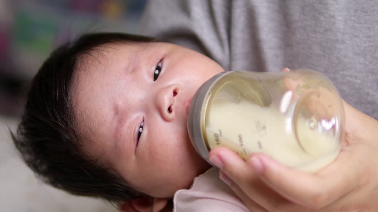 母親が新生児に母が持っている乳瓶で乳液をにする