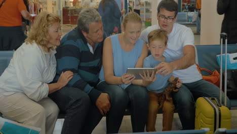 gran familia con tableta en la sala de espera