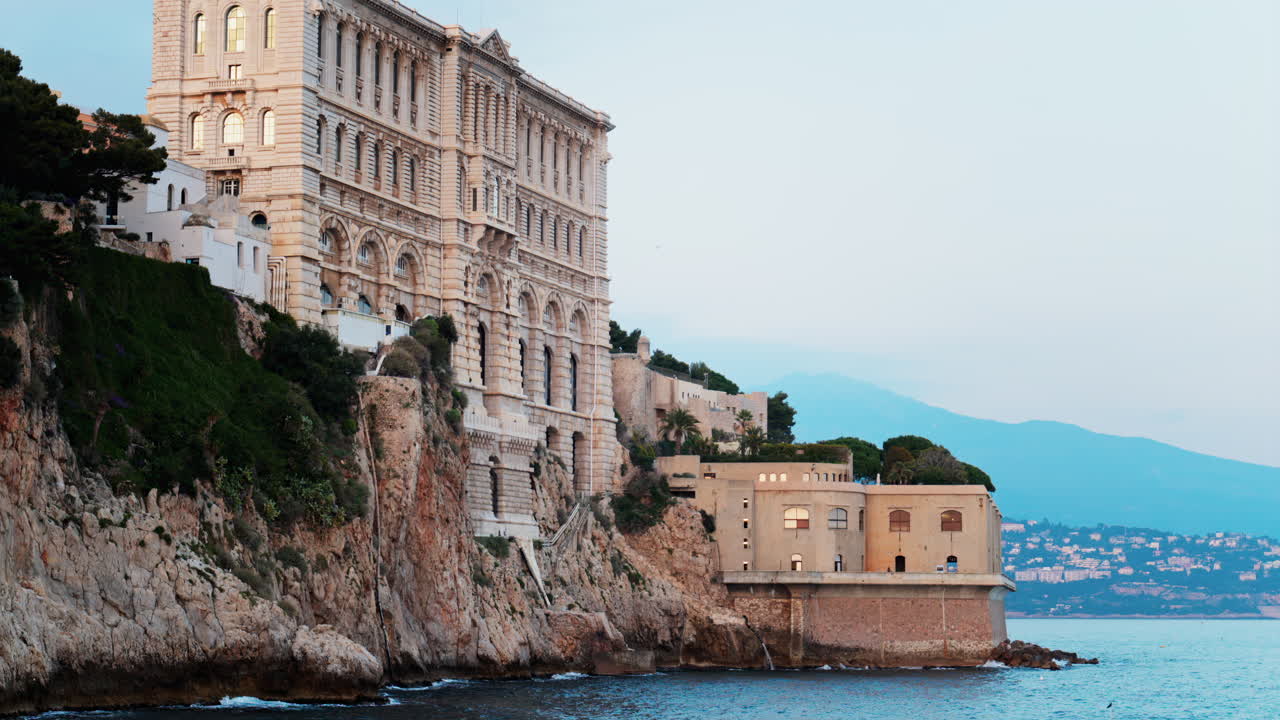 View of the The Oceanographic Museum of Monaco on the shore with the mountains on the background