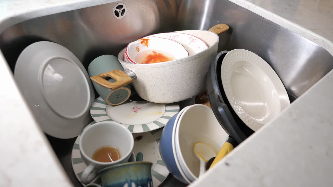 Pile of Dirty Dishes in a Stainless Steel Kitchen Sink