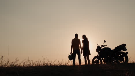 Siluetas-De-Una-Pareja-Joven-Cerca-De-Una-Motocicleta-1