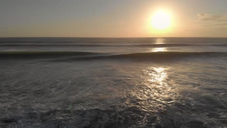 flying low and slowly over a wild ocean at sunset, with two rolling waves