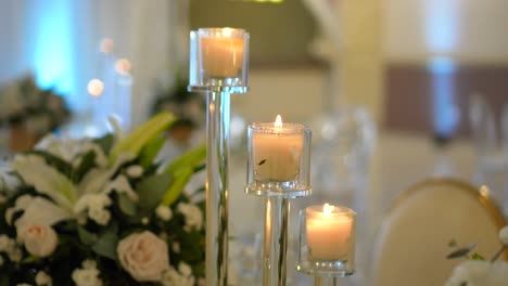 wedding room decorated with centerpieces of white roses and small candelabras with lit candles