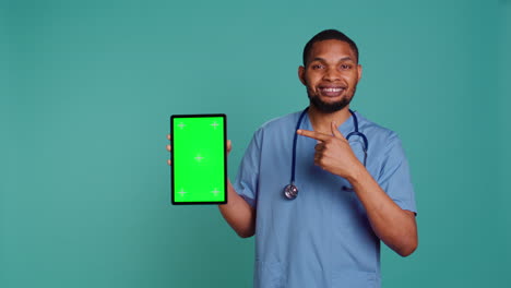 Portrait-of-male-nurse-showing-medical-instructions-video-on-green-screen-tablet