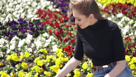 side view of female in casual outfit sitting on side of flowerbed