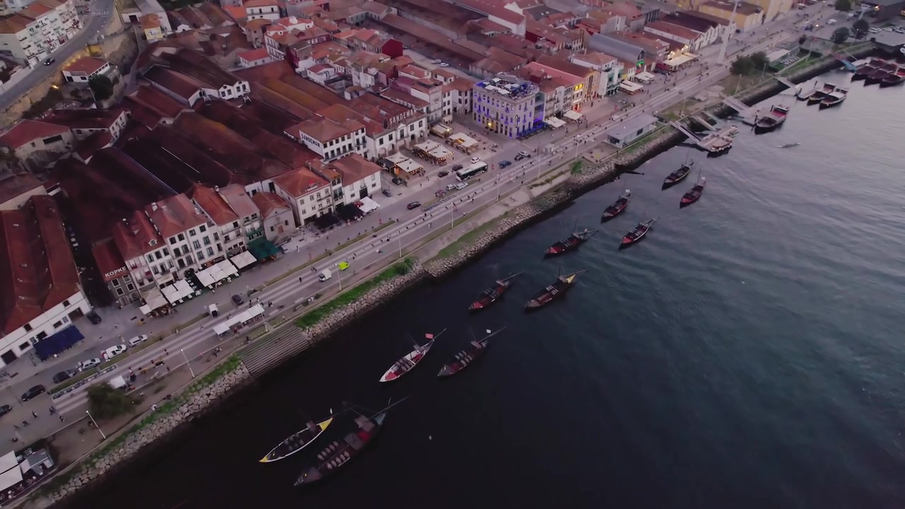 Barche Rabelo lungo il fiume Douro al lungofiume di Vila Nova de Gaia su Avenida de Diogo Leite nel comune di Porto, distretto di Porto, regione del Nord, Portogallo, con traffico stradale, ripresa drone obliqua in planata.