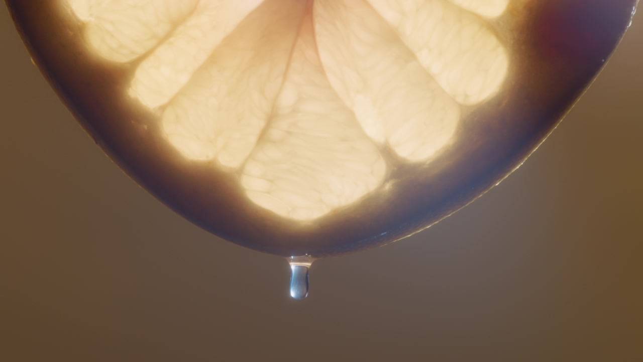 Macro shot of water drop falling from a white pomelo slice on yellow background