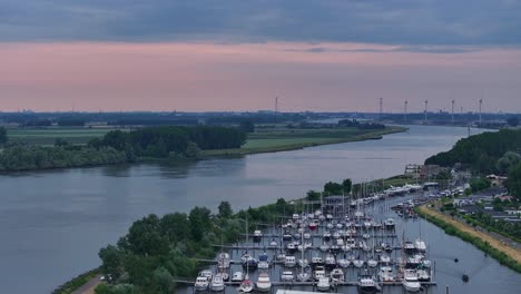 Luftaufnahme-Des-Hafens-Mit-Werft-Und-Festgemachten-Schiffen-Auf-Dem-Fluss-In-Der-Nähe-Von-Moerdijk-Nach-Sonnenuntergang