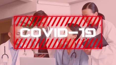 Covid-19-text-against-team-of-doctors-discussing-in-hospital