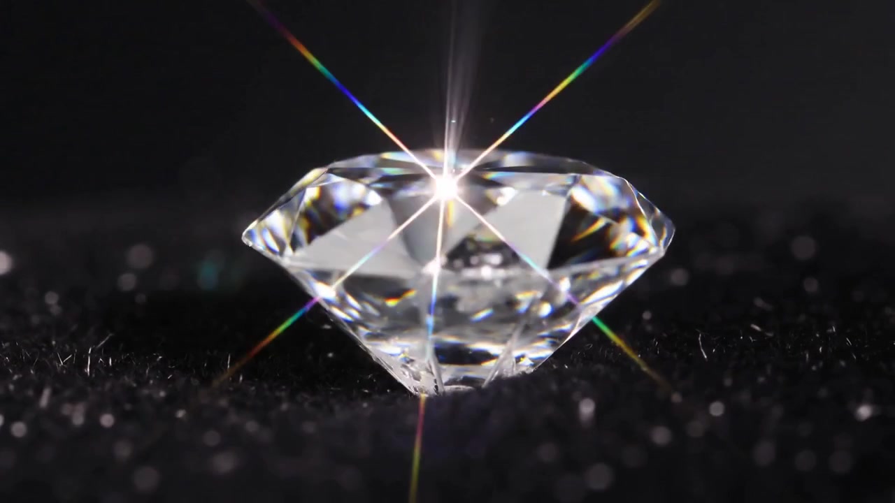 Luz puntual brillante creando un destello a través de un diamante redondo tallado sobre tela negra, mostrando sus facetas