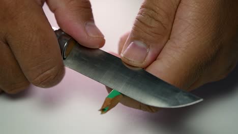 imágenes de manos afilando lentamente un lápiz y algunos lápices de colores con un cuchillo afilado