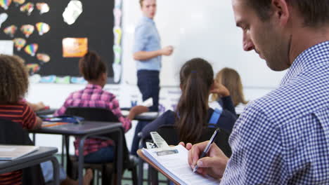 maestro en prácticas tomando notas en una lección de escuela primaria