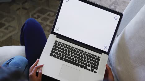 Biracial-sisters-sitting-on-sofa-and-using-laptop-with-copy-space,-in-slow-motion