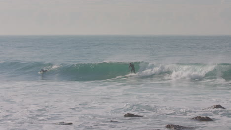 un surfista logra atrapar una ola mientras otros dos esperan la suya en malibu california