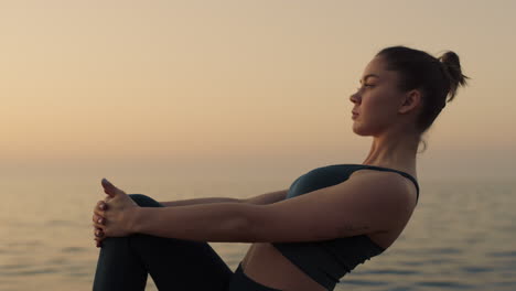 sportswoman raise up leg holding knee by hands outdoors. woman stretching feet.