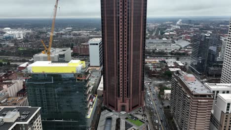 drone shot revealing supertall skyscraper bank of america plaza hiding in clouds, peachtree street traffic, aerial view