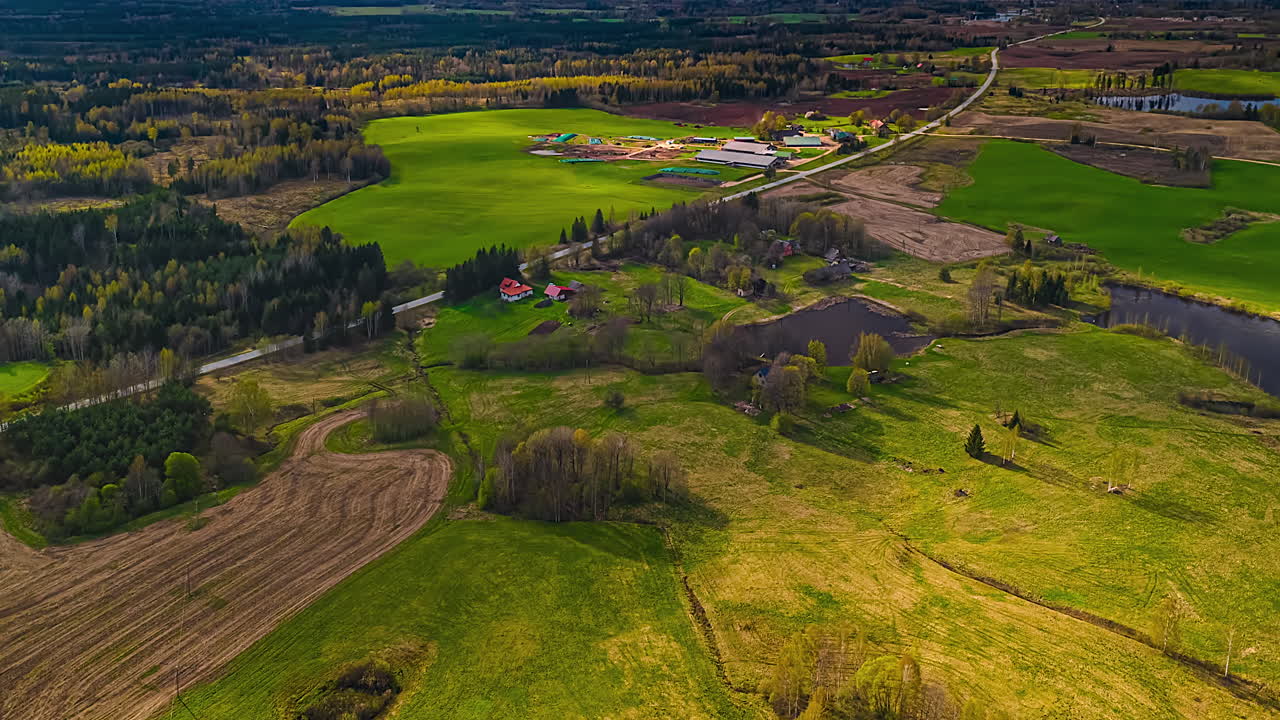 Timelapse aerial view of patchwork spring fields and farmland under golden light