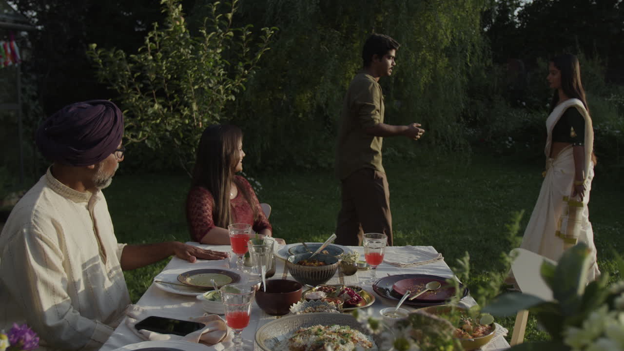 People enjoying an outdoor Indian family gathering in a garden