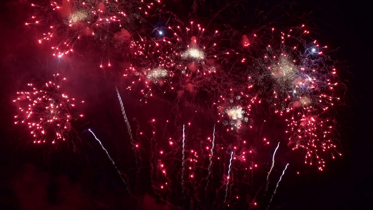el cielo nocturno se llena de fuegos artificiales rojos