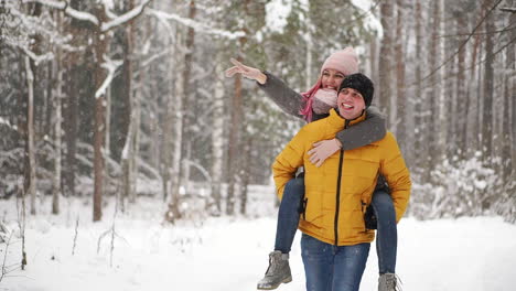 happy loving couple walking in snowy winter forest, spending christmas vacation together. outdoor seasonal activities. lifestyle capture.