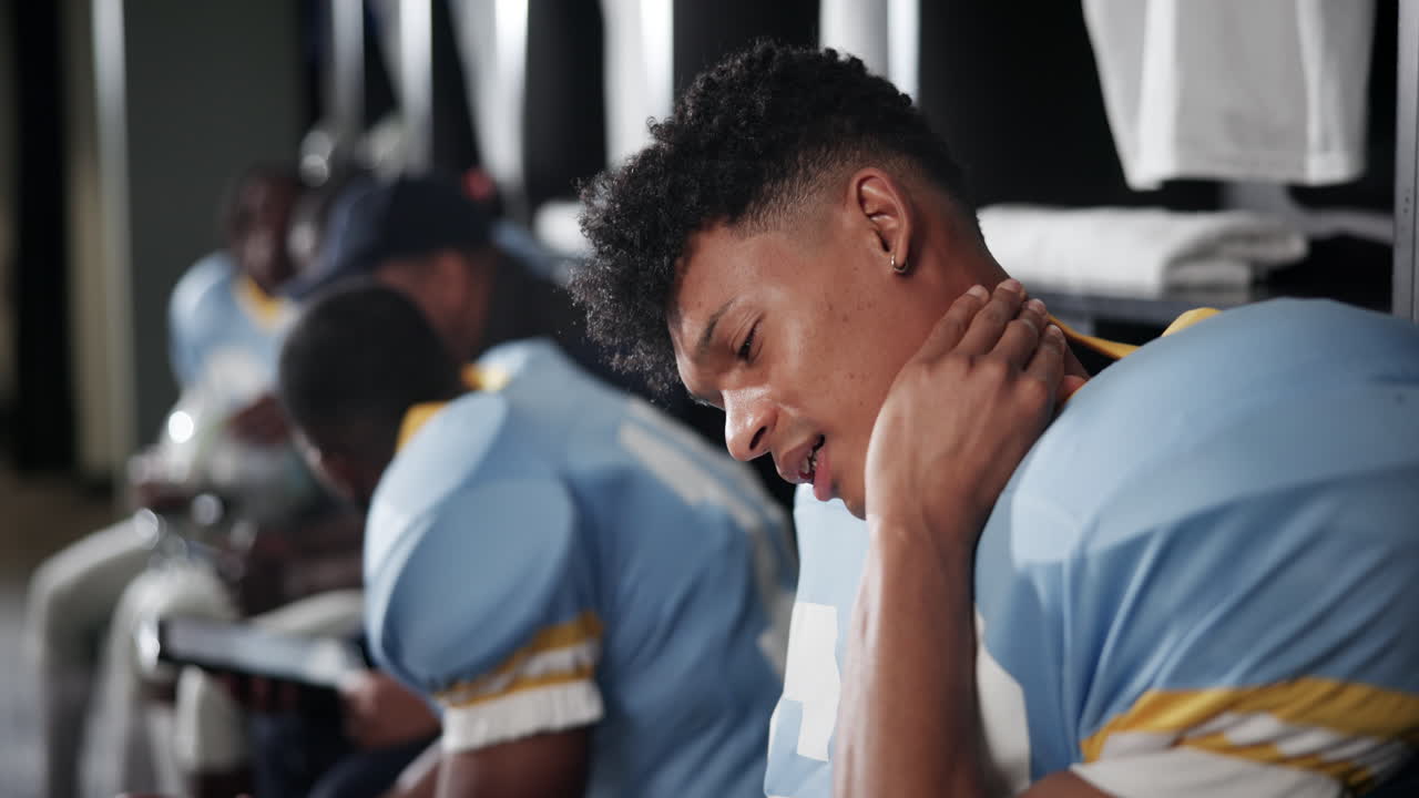 Football player with neck pain in locker room