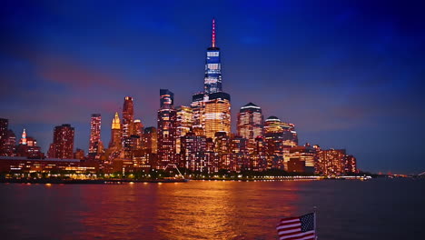 Bright city lights of New York skyline reflect in the waterscape of the river. Spectacular view on the city from the riverboat