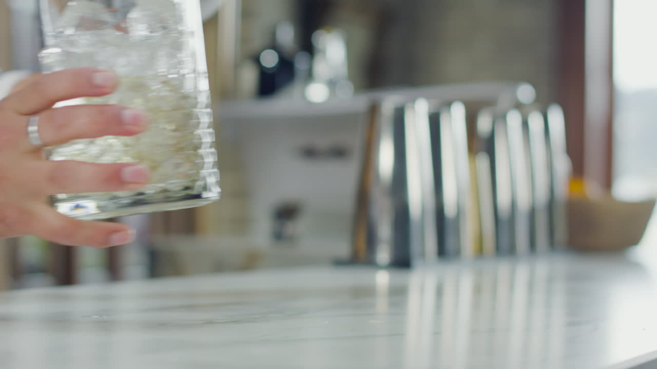 Bartender's hand taking an empty glass on a white bar