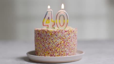 studio shot birthday cake covered with decorations and candle celebrating fortieth birthday being blown out