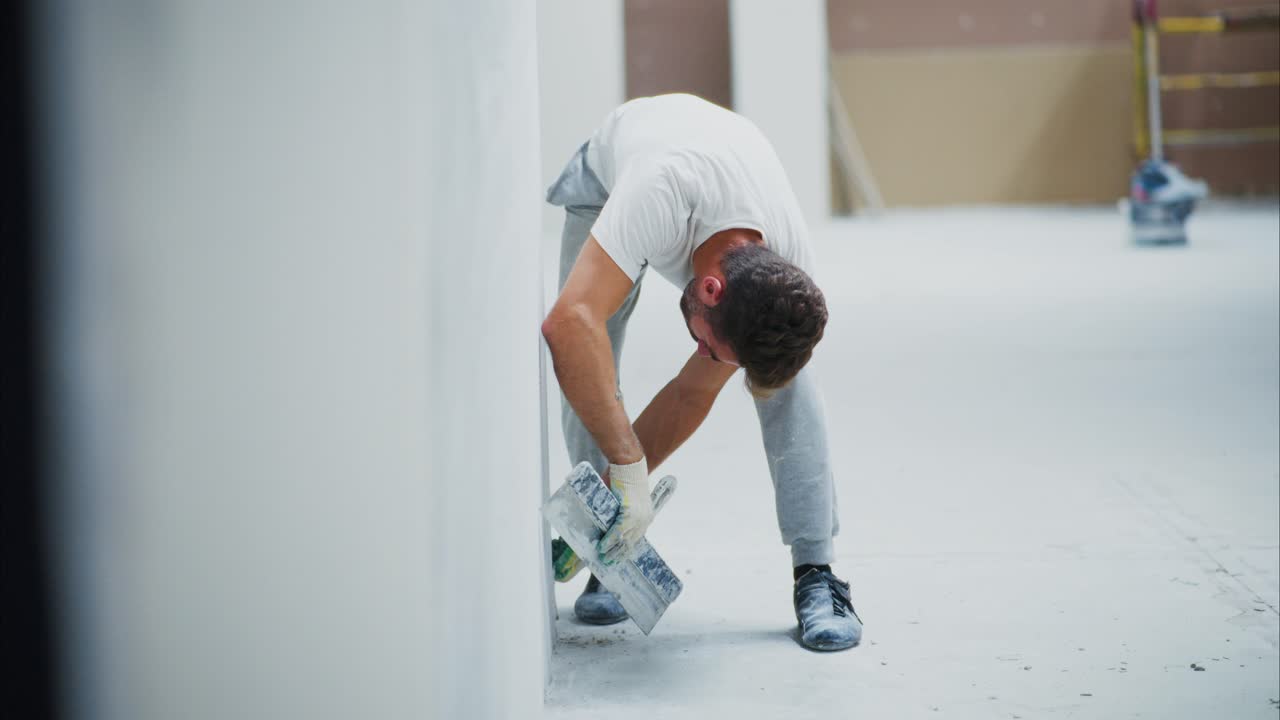 Skilled Craftsman Applying Finishing Touches to a Wall During Interior Renovation, Showcasing Precision and Attention to Detail with Trowel and Smooth Motion