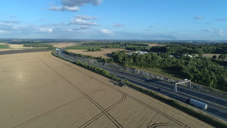 Einrichtung-Einer-Drohnenaufnahme-Eines-Mähdreschers-Neben-Der-Autobahn-An-Einem-Sonnigen-Tag-Zur-Goldenen-Stunde-In-Yorkshire,-Großbritannien