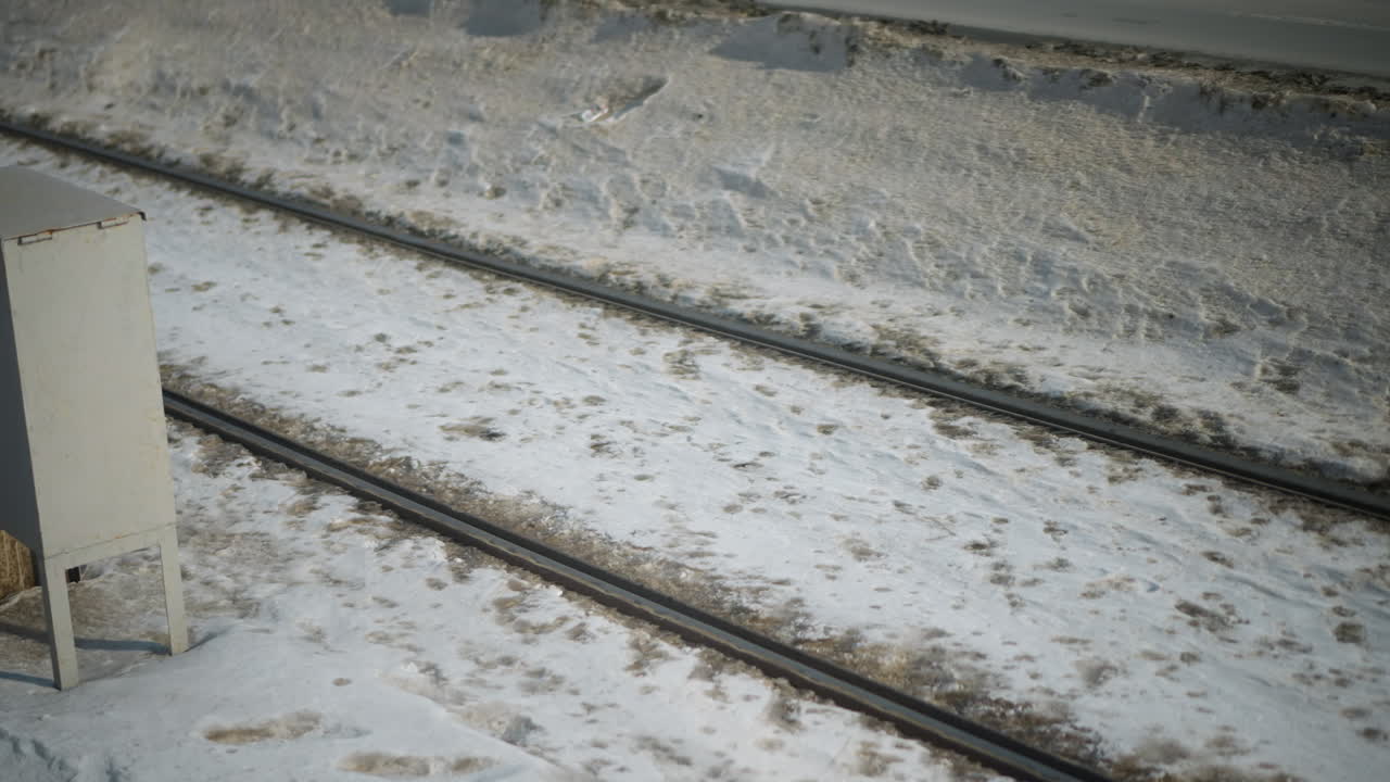 lower angle view of passenger stepping out from moving train onto snow covered ground, metal door ajar revealing motion blur outside, winter chill and travel urgency captured in fleeting moment