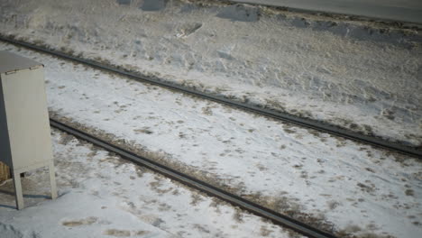 lower angle view of passenger stepping out from moving train onto snow covered ground, metal door ajar revealing motion blur outside, winter chill and travel urgency captured in fleeting moment