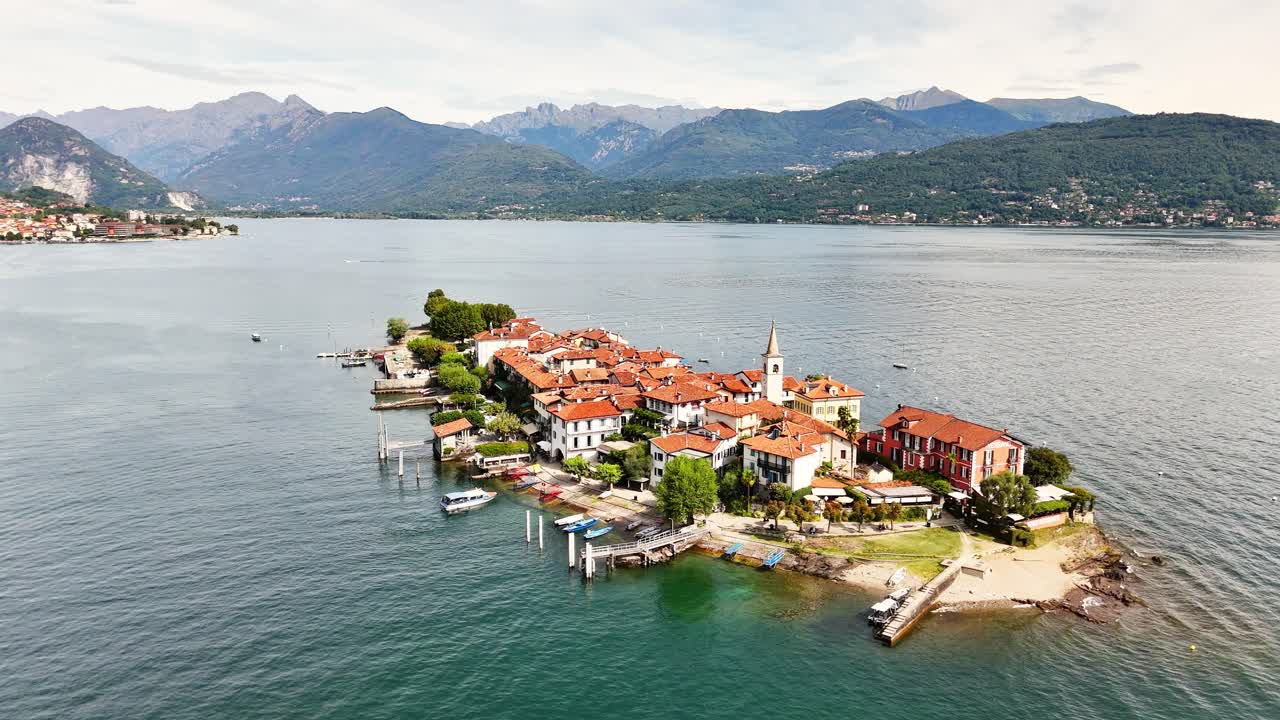 Isola Bella, a picturesque island village on Lake Maggiore, Stresa, showcases charming architecture, docks, and boats, surrounded by the western Alps landscape of northern Italy, Piedmont, drone orbit