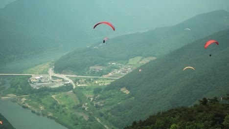 패러글라이더가 한국 단양의 산 사이로 내려오고, 도시가 공중에서 내려다 보입니다.