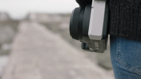 fotógrafo de mujer caminando solo en la playa con la cámara explorando solo