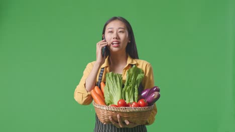 woman talking on phone with basket of vegetables