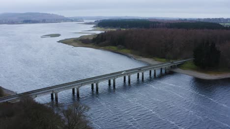 Bridging-Horizons:-Aerial-Journey-to-Baltyboys-Bridge-over-the-River-Liffey-in-the-Wicklow-Mountains,-Amidst-a-Cloudy-Evening-Drive