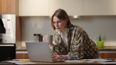 Beautiful-woman-enjoying-a-hot-chocolate-while-browsing-on-social-media-sitting-down-relaxed-on-couch-at-home