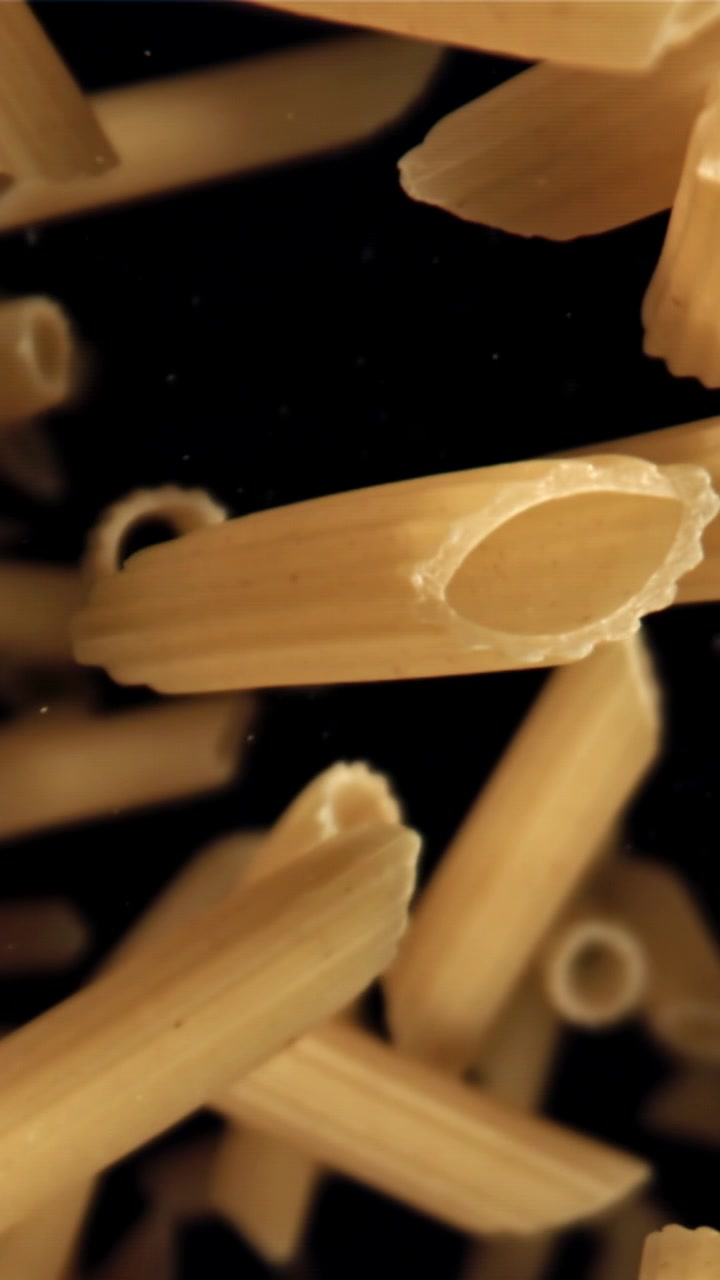 Pasta Penne Cruda che Cade al Rallentatore su Sfondo Nero
