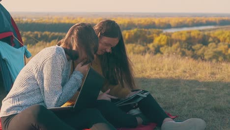 girl with laptop looks at friend tablet in camp slow motion