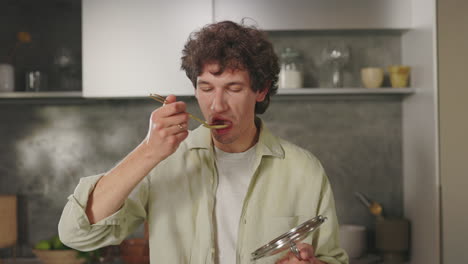 man tasting and reacting to food in the kitchen