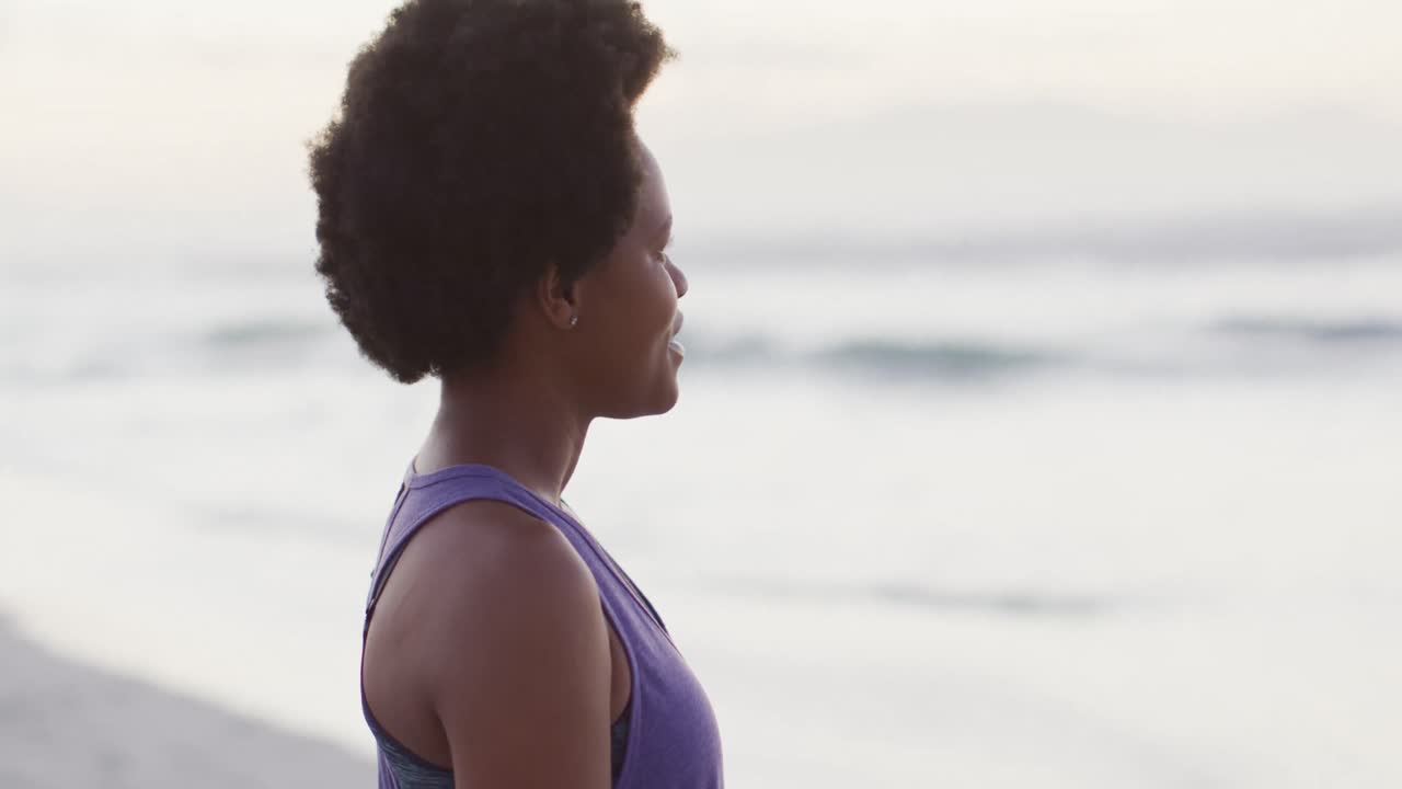 Portrait of happy african american woman wearing sports suit on sunny beach
