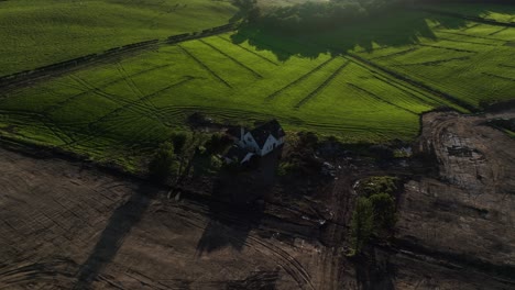 Aerial-rotating-shot-of-a-small-house-with-the-ground-dug-up-beside-for-construction