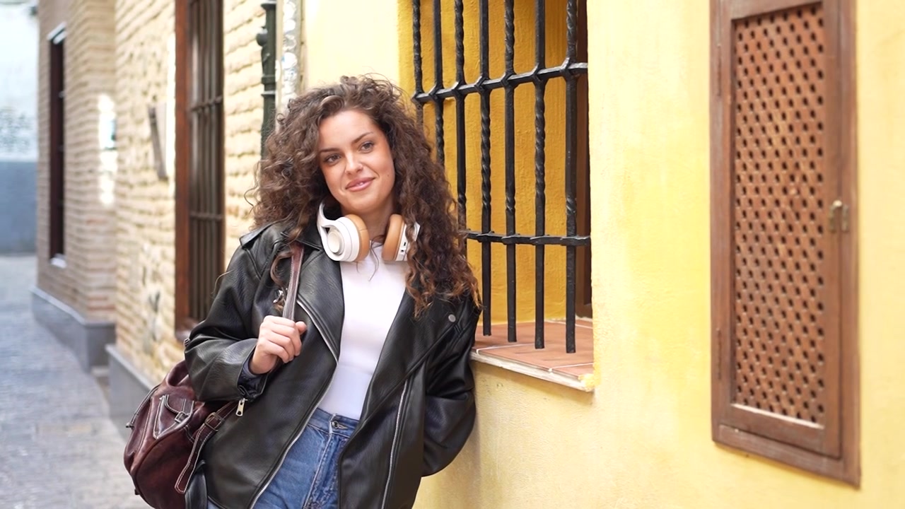 Una giovane donna elegante e alla moda con un outfit chic è appoggiata a un muro con sicurezza.