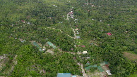 slow drone video over green exotic jungle in foreign country with town and people below