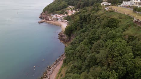 Sobrevuelo-Aéreo-Hermoso-Paisaje-Con-Acantilados-Verdes-Y-Playa-Rocosa-Y-Costa-Azul-En-La-Ciudad-De-Torquay,-Devon