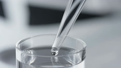 close-up of a dropper dispensing liquid into a beaker